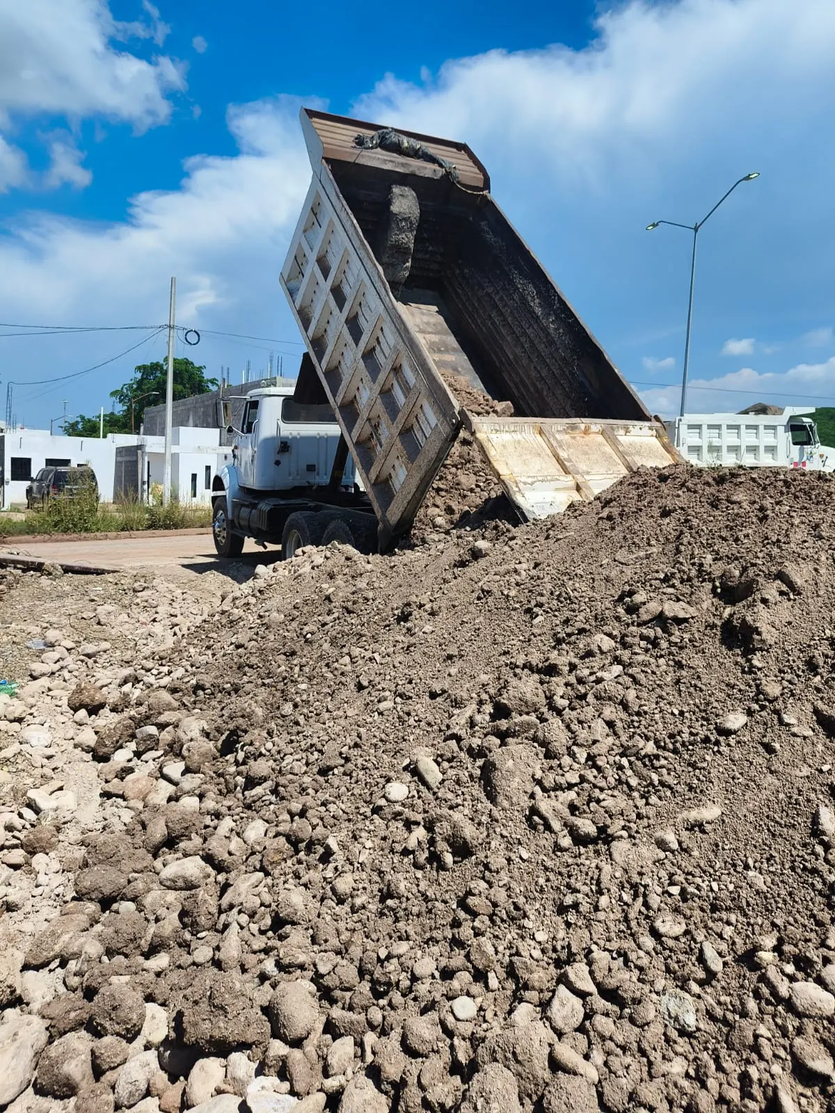 Camión de volteo descargando material de relleno